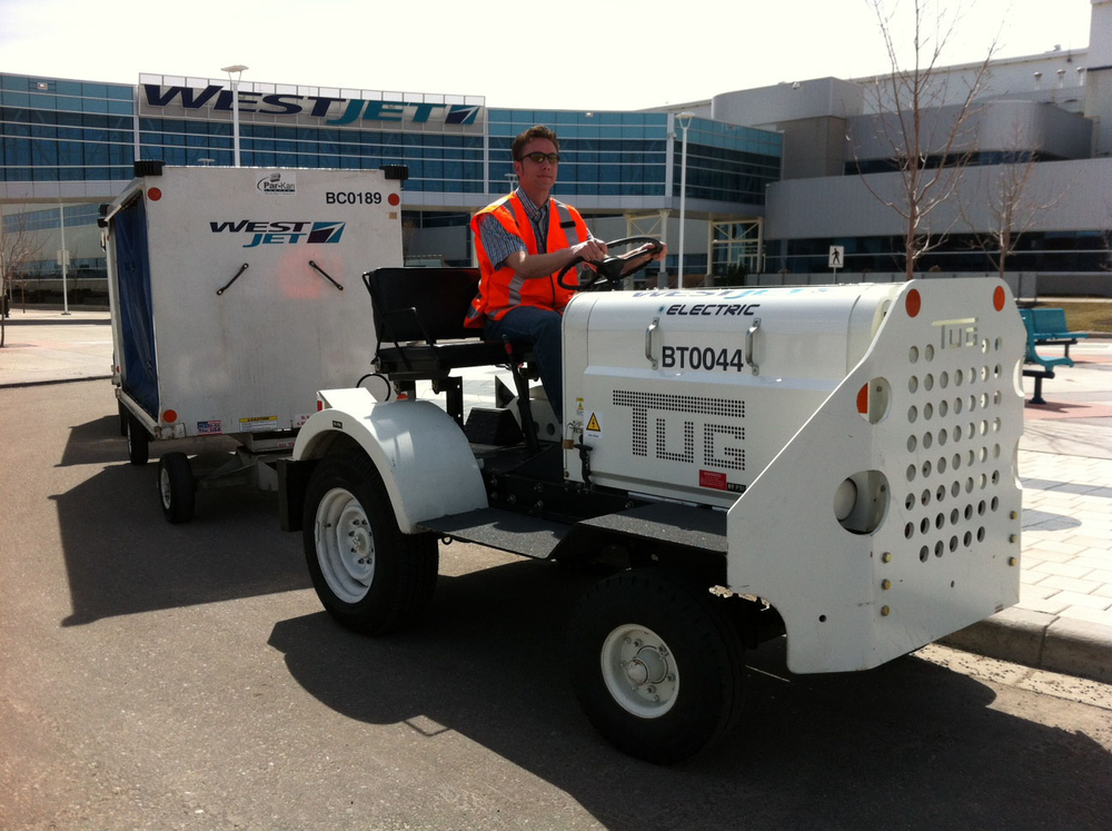 WestJetter Leigh Hoey sits atop a lithium polymer-powered baggage tug, developed in partnership with Corvus Energy of Richmond, BC. (CNW Group/WestJet)