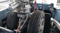 Two major components of the Taxibot make it different from other towbarless tractors: An interface mechanism clamps on the nose landing gear, which is in turn mounted on a “rotating turret.' Two major components of the Taxibot make it different from other towbarless tractors: An interface mechanism clamps on the nose landing gear, which is in turn mounted on a “rotating turret.'