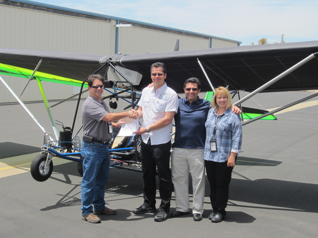 FAA Aviation Safety Inspectors John Soltis (L) and Kym Robbins (R), hand pink airworthiness certificate to Quicksilver Aeronautics principals Will Escutia (white shirt) and Dan Perez at the French Valley Airport.