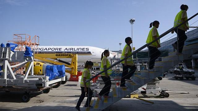 Cleaners from ground handler SATS walk up the staircase to an airplane. SATS workers recover thousands of items left on planes every year.