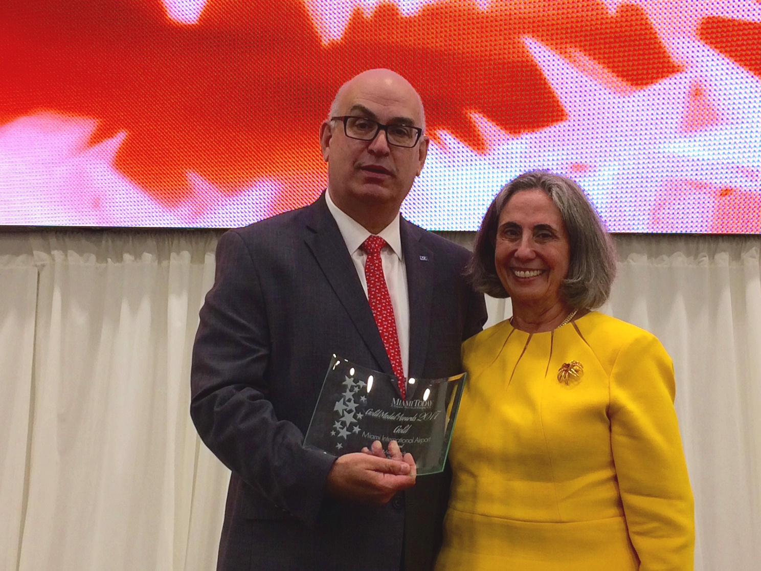 From left: MIA Director Emilio T. Gonz&aacute;lez receives the airport&rsquo;s Miami Today 2017 Gold Medal Award from Teresa Vald&eacute;s-Fauli Weintraub, Merrill Lynch Managing Director.