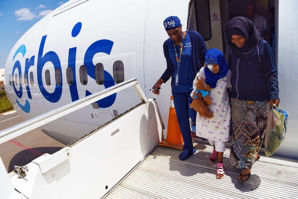 Orbis staff nurse Gloria Rhomes assisted Rahmet, age 9, from the Flying Eye Hospital after her cataract surgery in Addis Ababa, Ethiopia.