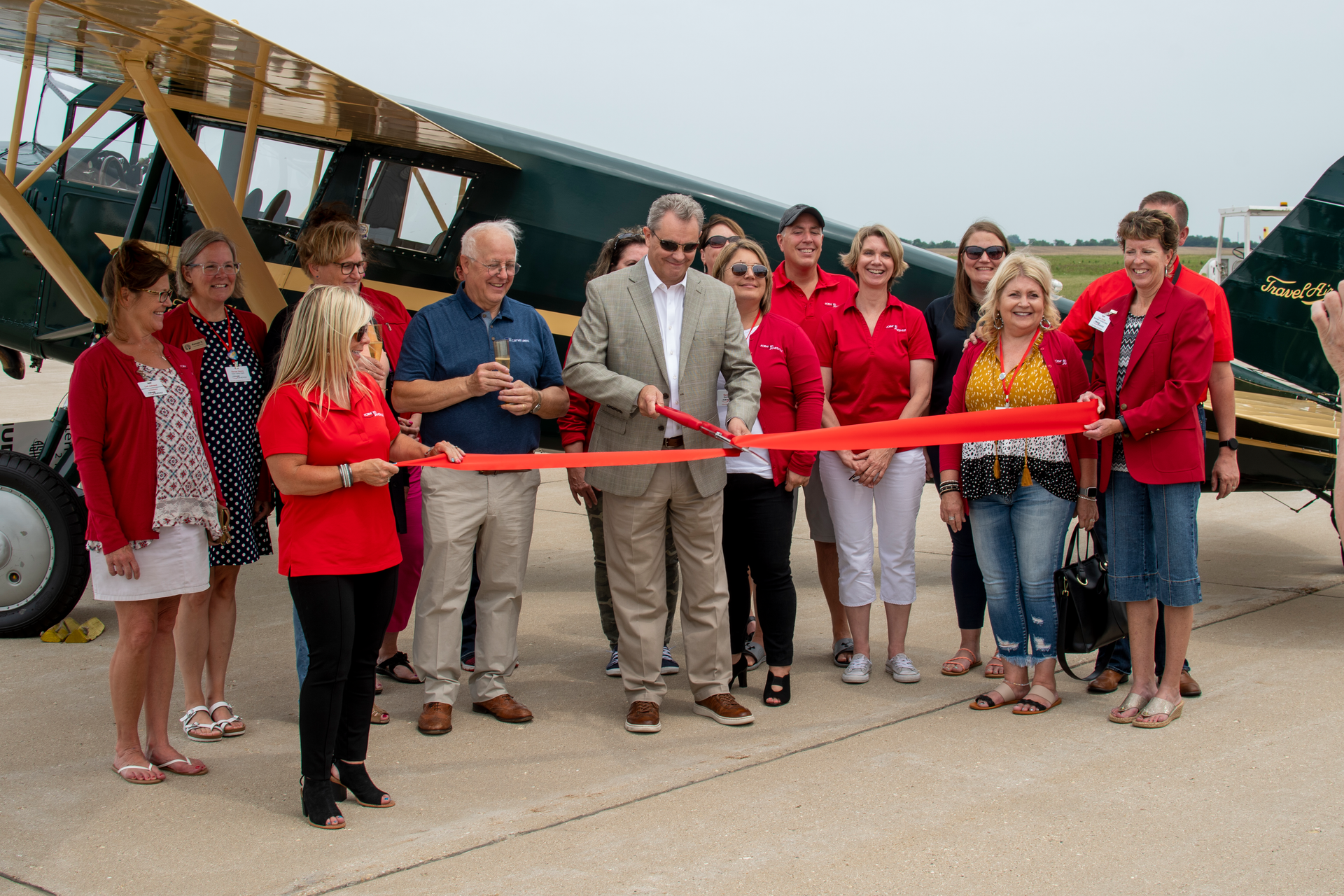 Guy Lieser, center, with Peter Limberger, left, cut the ribbon on the Janesville Jet Center in front of the 1929 Travel Air Model 10-D airplane.