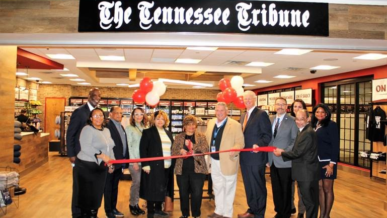 Nov. 19 guests celebrate the grand opening of The Tennessee Tribune store at Nashville International Airport with Tribune founder and publisher/CEO Rosetta Miller-Perry in a special tribute to her 30-year legacy. The state&rsquo;s largest minority newspaper marks three decades serving the African-American community. Pictured left to right are Davita Taylor, vice president, Procurement & Business Diversity, Metropolitan Nashville Airport Authority (MNAA); Forrest E. Harris Sr., president, American Baptist College; Michael Hooks; Janet Hooks; Wanda Miller-Benson (Rosetta&rsquo;s daughter); Rosetta Miller-Perry (center, holding scissors); Bill Freeman, chairman, MNAA Board of Commissioners; Doug Kreulen, president and CEO, MNAA; Matt Jennings, vice president, Fraport Tennessee; Jennifer Winchester, ACDBE partner, TRNA Nashville; Steve Benson; and Juney June, The Tennessee Tribune.