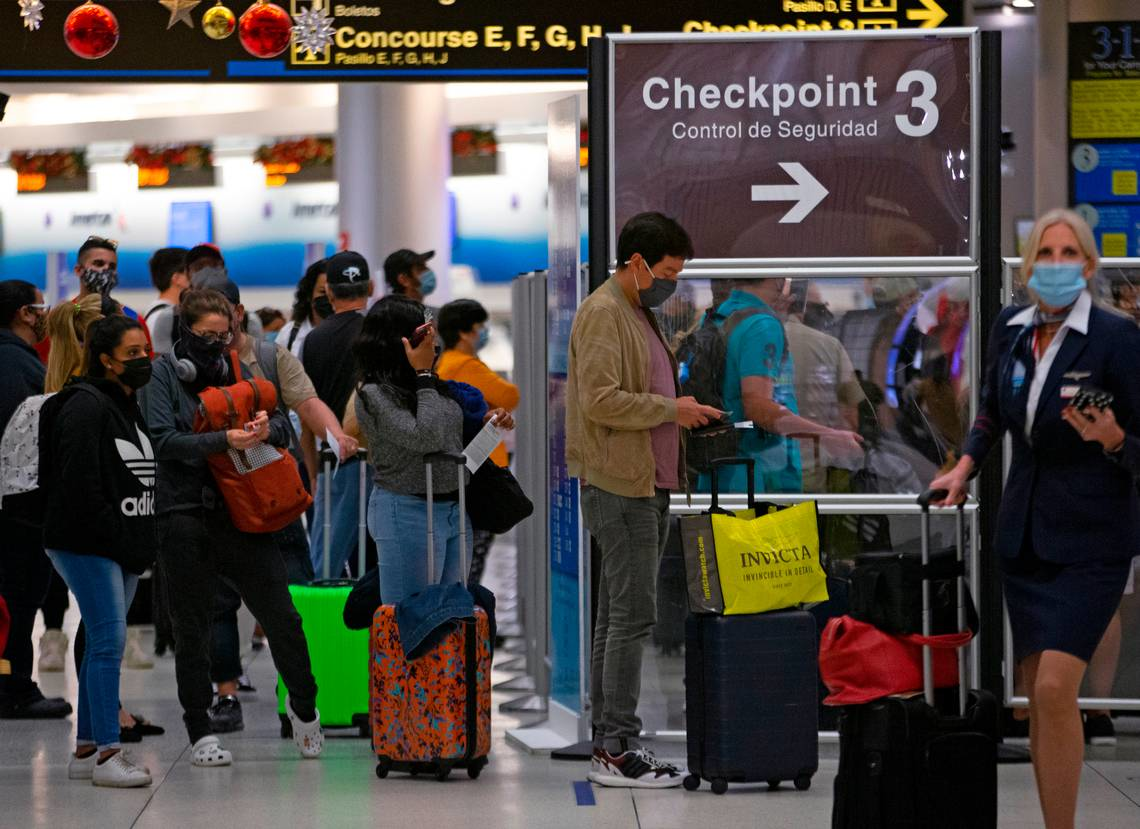 Travelers wearing protective face masks line up to pass through a security checkpoint at Concourse D at Miami International Airport on Monday, Dec. 28, 2020. A survey published in March 2022 found MIA had the longest average wait times for security and passport control among the nation s largest airports.