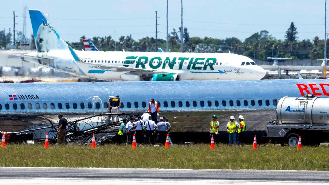 National Transportation Safety Board agents, Federal Aviation Administration agents and Miami-Dade Fire Rescue crews surround RED Air Flight 203 which crash-landed with a fiery emergency landing Tuesday evening, on the tarmac at Miami-International Airport in Miami, Florida, on Wednesday, June 22, 2022.
