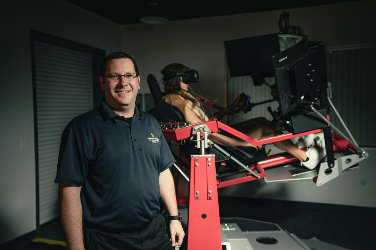 Dr. Bob Thomas, an assistant professor of Aeronautical Science who heads up Embry-Riddle Aeronautical University&rsquo;s Spatial Disorientation Laboratory, stands near its new simulator, which is being used by student Nella Filipkova.