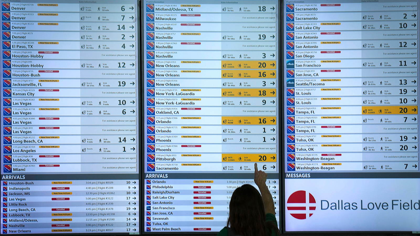 Flight status boards show Southwest flights either canceled or delayed up and down the board at Dallas Love Field.