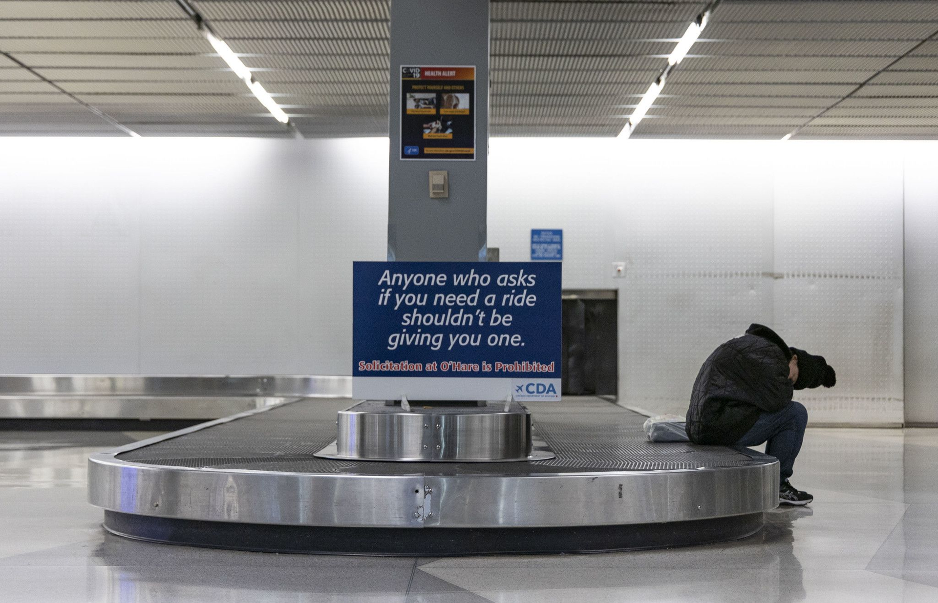 A homeless person sleeps inside Terminal 2 baggage claim on Jan. 19, 2023, at O Hare International Airport.
