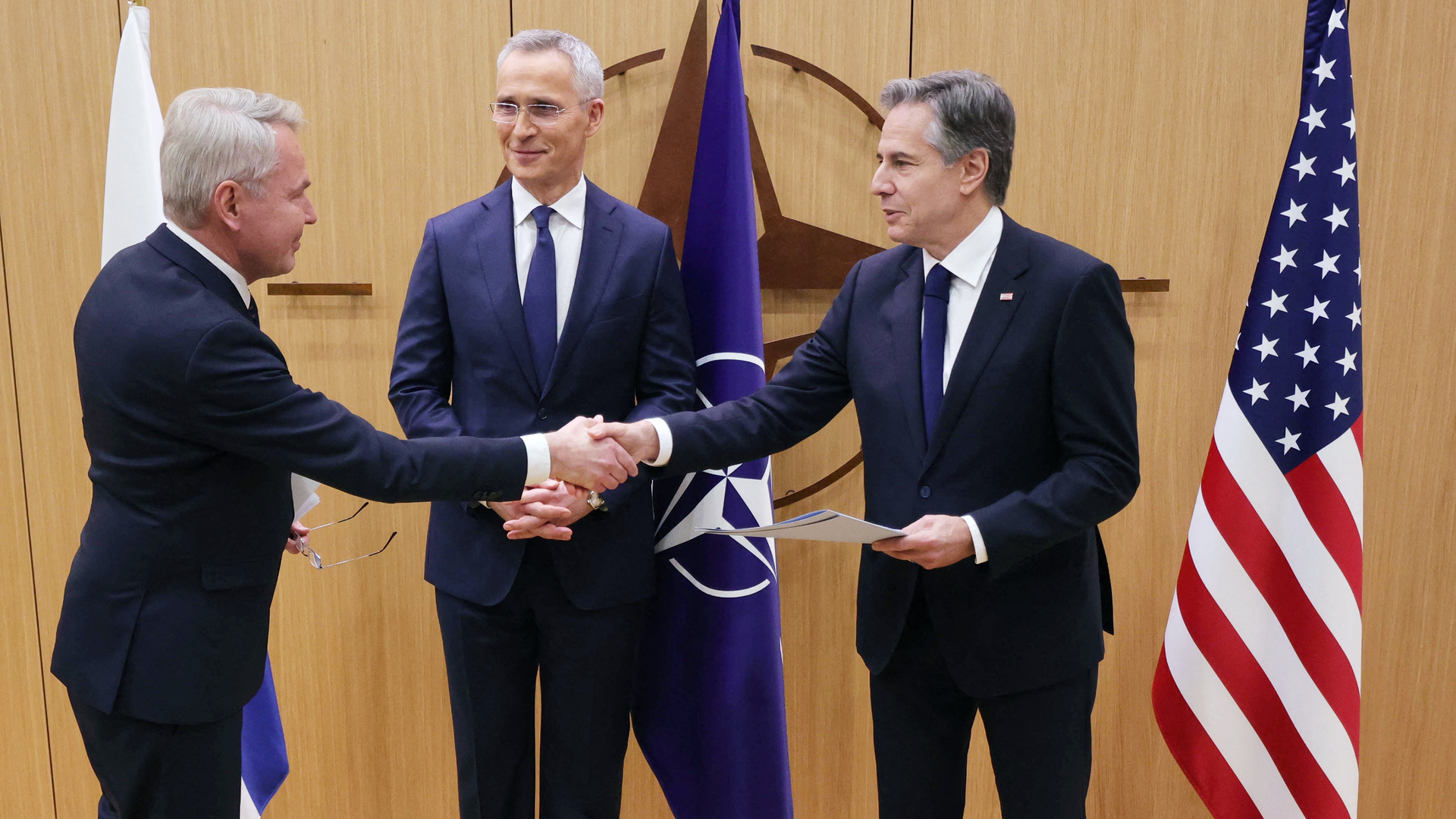 Finnish Foreign Affairs Minister Pekka Haavisto (L) shakes hands with US Secretary of State Antony Blinken, flanked by NATO Secretary-General Jens Stoltenberg (C) as he hands over Finland's accession to NATO documents, during a joining ceremony at a NATO - North Atlantic Council (NAC) Foreign Affairs ministers' meeting, at the NATO headquarters in Brussels, on April 4, 2023. - Finland on April 4 became the 31st member of NATO, wrapping up its historic strategic shift with the deposit of its accession documents to the alliance.
