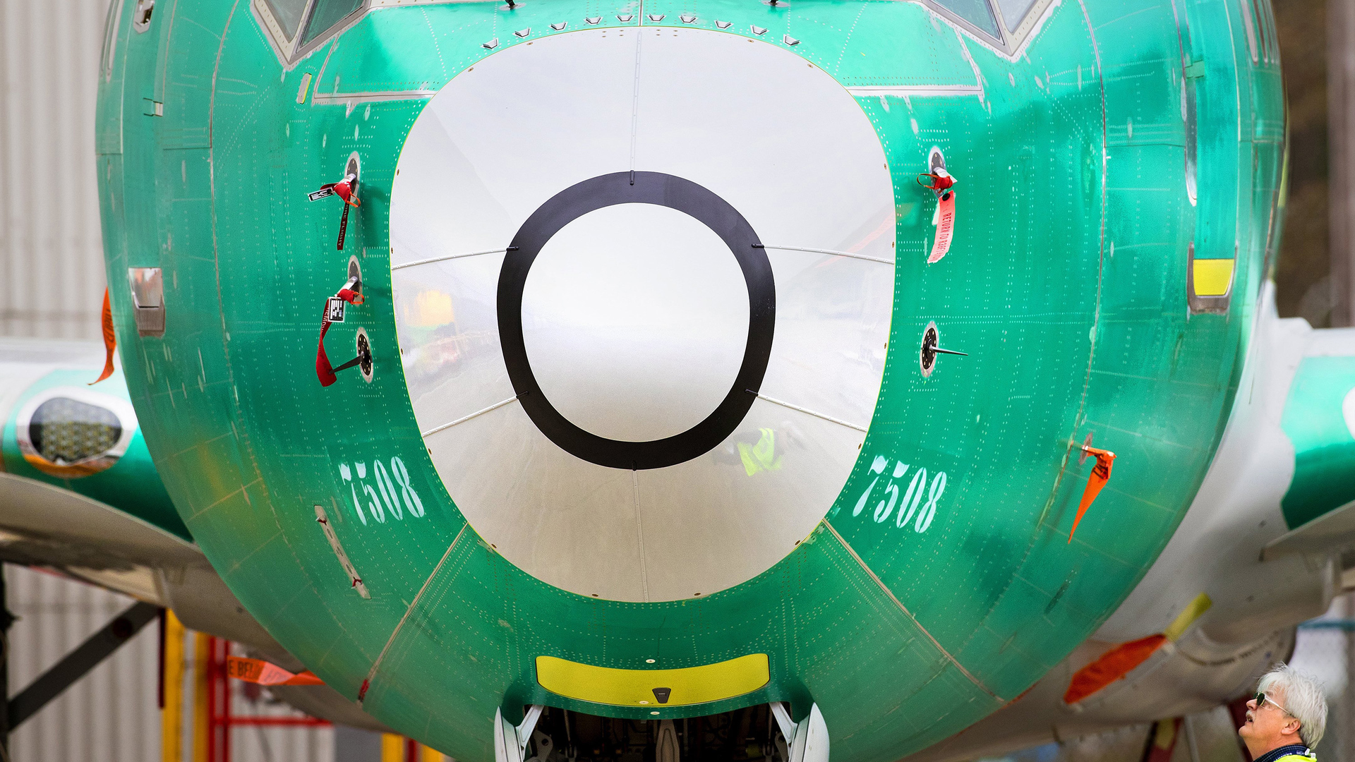 A Boeing employee looks up toward the sensor measuring the plane's angle of attack just below the cockpit of a 737 MAX 8 plane sitting outside the 737 factory in Renton, Washington on March 25, 2019.