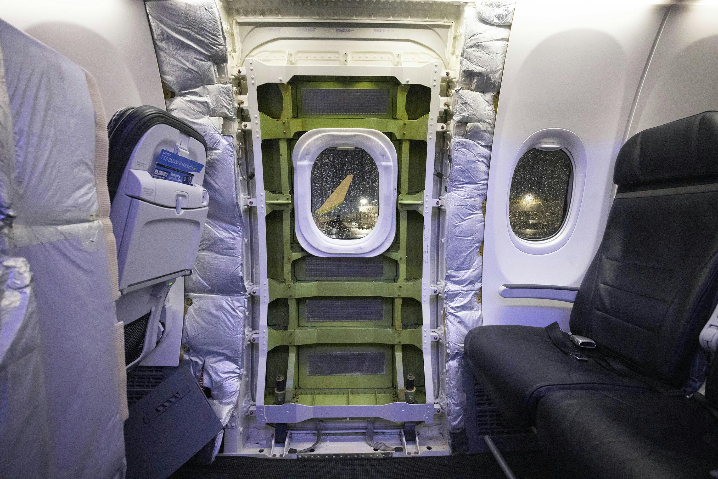 A panel has been removed that covered the door plug on a Boeing 737-9 Max parked near an Alaska Airlines hangar at SEA on Jan. 11, 2024. Four bolts and 12 stop fittings hold the door plug in place.