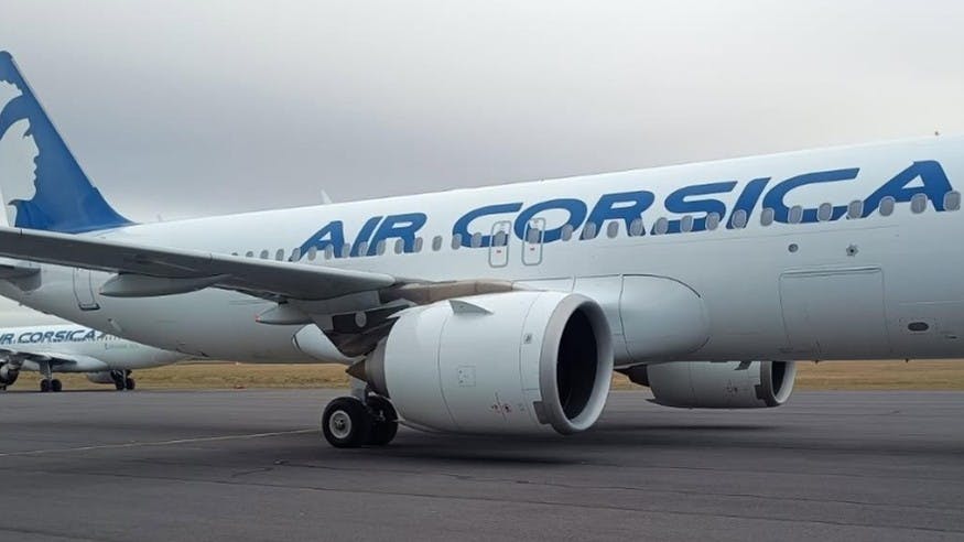 A white airplane with a blue fin and blue lettering that says 'Air Corsica'