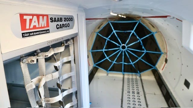 The interior of a plane with no seating and added straps to tie down cargo