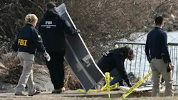 A group of people with 'FBI' on their sweatshirts investigates a pile of aircraft wreckage A group of people with 'FBI' on their sweatshirts investigates a pile of aircraft wreckage