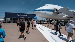 A wide shot of Boeing Plaza at EAA AirVenture, showcasing an airplane, a crowd of people and a building with the word 'BOEING' on it A wide shot of Boeing Plaza at EAA AirVenture, showcasing an airplane, a crowd of people and a building with the word 'BOEING' on it