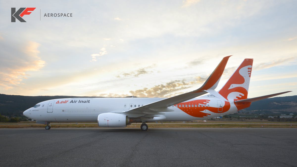 A white airplane with red detailing and text on the side that reads, 'Air Inuit' sits on a tarmac with floating text above it that says, 'KF Aerospace'
