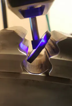 A piece of technological equipment taking close measurements of a curvy piece of metal A piece of technological equipment taking close measurements of a curvy piece of metal