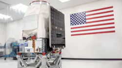 A Saturn-200 minisatellite sitting in a white room with an American flag behind it A Saturn-200 minisatellite sitting in a white room with an American flag behind it
