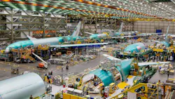 A hangar showing airplanes and machinery with people working around the machines A hangar showing airplanes and machinery with people working around the machines