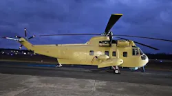 A beige helicopter parked on a tarmac in dim evening lighting A beige helicopter parked on a tarmac in dim evening lighting
