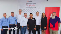 A line of people in business attire standing in front of a backdrop that reads, 'Unilode Grand Opening Ceremony Los Angeles MRO Centre' A line of people in business attire standing in front of a backdrop that reads, 'Unilode Grand Opening Ceremony Los Angeles MRO Centre'