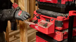 A gloved hand holding a nail next to a toolbox with a compartment on the side filled with nails and screws A gloved hand holding a nail next to a toolbox with a compartment on the side filled with nails and screws
