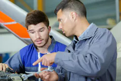Two aircraft maintenance technicians talking to each other next to an airplane Two aircraft maintenance technicians talking to each other next to an airplane