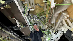 A technician working on electrical wires underneath an open ceiling with wires and ducts showing A technician working on electrical wires underneath an open ceiling with wires and ducts showing