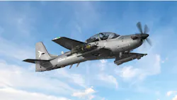 A dark gray military aircraft flying in a blue sky, with the words 'A-29 Super Tucano' printed on the side A dark gray military aircraft flying in a blue sky, with the words 'A-29 Super Tucano' printed on the side