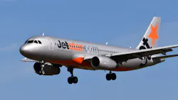 A gray airplane flying in a blue sky with blue and orange text on the side that reads: Jet Star A gray airplane flying in a blue sky with blue and orange text on the side that reads: Jet Star