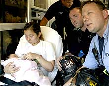 Gloria Reyes and daughter Emily are safe and sound after Fire Capt. Tom Riley (right) and firefighter Michael McCrory (center) scaled a ladder to rescue them yesterday from a fire in their fourth-floor apartment in East Elmhurst.
