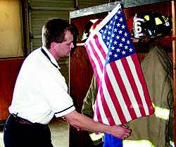Vann's Crossroads Fire Chief Jamey Jones hangs a flag over Phillip Hulen's turn out gear on Wednesday