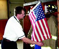 Vann's Crossroads Fire Chief Jamey Jones hangs a flag over Phillip Hulen's turn out gear on Wednesday Vann's Crossroads Fire Chief Jamey Jones hangs a flag over Phillip Hulen's turn out gear on Wednesday