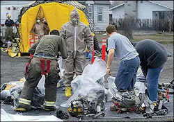 Yakima County Fire District firefighters remove and bag their gear before entering a decontamination tent in Grandview, Wash., Wednesday afternoon, Jan. 26, 2005. A burning warehouse containing farm chemicals at Wilbur-Ellis Co. sent contaminated smoke into the foggy air, prompting authorities to evacuate nearby homes and businesses. Yakima County Fire District firefighters remove and bag their gear before entering a decontamination tent in Grandview, Wash., Wednesday afternoon, Jan. 26, 2005. A burning warehouse containing farm chemicals at Wilbur-Ellis Co. sent contaminated smoke into the foggy air, prompting authorities to evacuate nearby homes and businesses.