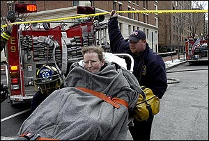 A rescue worker helps an unidentified woman from a fire at a senior citizens living center in Washington, Tuesday, March 1, 2005. Smoking materials are being blamed for the fire in a fifth floor apartment at a Foggy Bottom senior citizens building. Seven people were evaluated after being led out of Saint Mary's Court. One firefighter also suffered minor injuries.