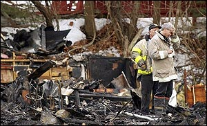 A firefighter holds his hand to his forehead as he stands amidst the rubble at the scene of a deadly fire at The Station nightclub in West Warwick, R.I. in this Feb. 21, 2003 file photo. After a two-year investigation into what caused a West Warwick nightclub to become a deadly firetrap, a panel of experts on Thursday planned to release recommendations to keep a similar tragedy from happening again.