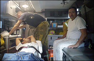 Seen through the window of an emergency service vehicle, a Los Angeles Fire Department paramedic, rear, attends to two building painters Thursday, March 3, 2005, in downtown Los Angeles. Firefighters broke a window to rescue the painters who spent about 40 minutes dangling from a 10-story building after their scaffolding collapsed beneath them. Neither worker was injured.