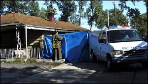 Firefighters use a tarp to block the view of a body being removed from a home in Gary, Ind., Wednesday Sept. 21, 2005. Bars on the windows may have kept victims from escaping a house fire that killed three children and two adults early today in Gary, Indiana. A fire department inspector says nine people were inside the house, and two are hospitalized in serious condition. The cause has not been determined.