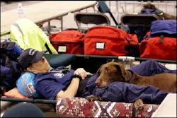 Kim Norman,of the Phoenix Fire Department, rests on a cot with rescue dog Reo as they wait in Houston for winds from Hurricane Rita to subside enough to fly over storm wrecked areas and assess the damage Saturday, Sept. 24, 2005. Kim Norman,of the Phoenix Fire Department, rests on a cot with rescue dog Reo as they wait in Houston for winds from Hurricane Rita to subside enough to fly over storm wrecked areas and assess the damage Saturday, Sept. 24, 2005.