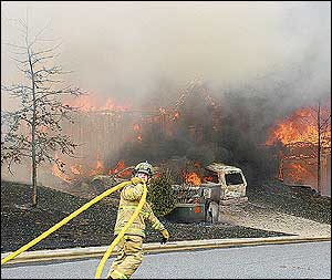 A firefighter moves a hose down the street while trying to stay ahead of a fast-moving fire that destroyed four homes in the Bethelview Downs subdivision in Cumming.