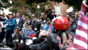 Families of fallen firefighters take pictures as the motorcyclists arrive on the campus of the National Fire Academy.