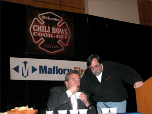 NFFF Executive Director Ron Siarnicki judges chili with emcee Billy Goldfeder looking on.