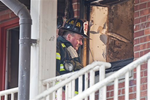 A firefighter looks into the window of the fire damaged apartment in the P.T. Barnum complex in Bridgeport, Conn., Friday, Nov. 13, 2009.
