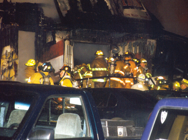 Metal handrail and parked vehicles impede recovery efforts at the front entryway. A window to the bar room is at left.