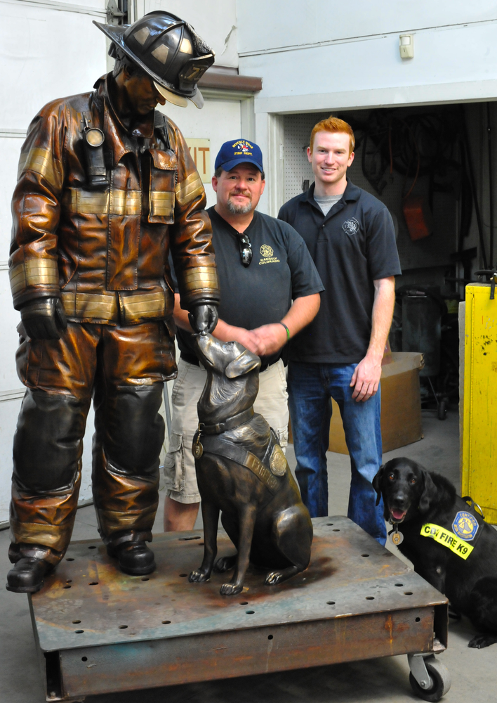 Arson Investigator Jerry Means, left, and Firefighter Austin Weishel stand next to the monument they both helped create.