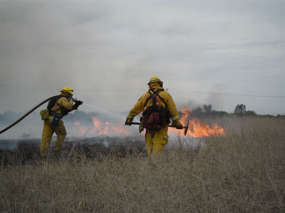 Firefighter Rose Grier (CAL FIRE San Diego Unit - Lyons Valley Fire Station) puts out a wildland fire in a scene from 'Lives on Fire' on OWN.