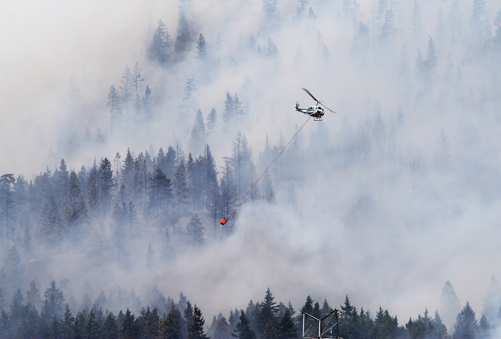A firefighting helicopter, operated by the Washington State Department of Natural Resources, works to supress the Taylor Bridge Fire east of Cle Elum, Wash. on Aug. 13.