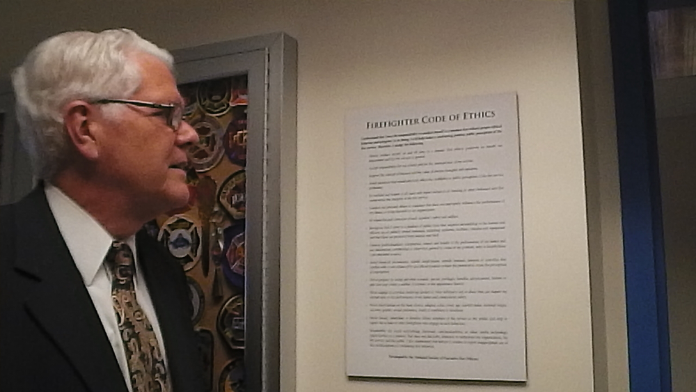 National Fire Academy Superintendent Dr. Denis Onieal looks at a copy of the Code of Ethics on the campus in Emmitsburg, Md.