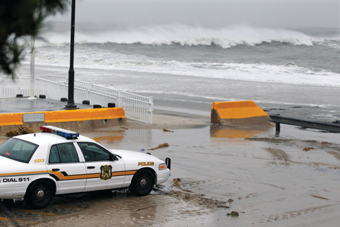 A police officer watches from his patrol car as the rough Atlantic Ocean threatens streets on Oct. 29 in Cape May, N.J.